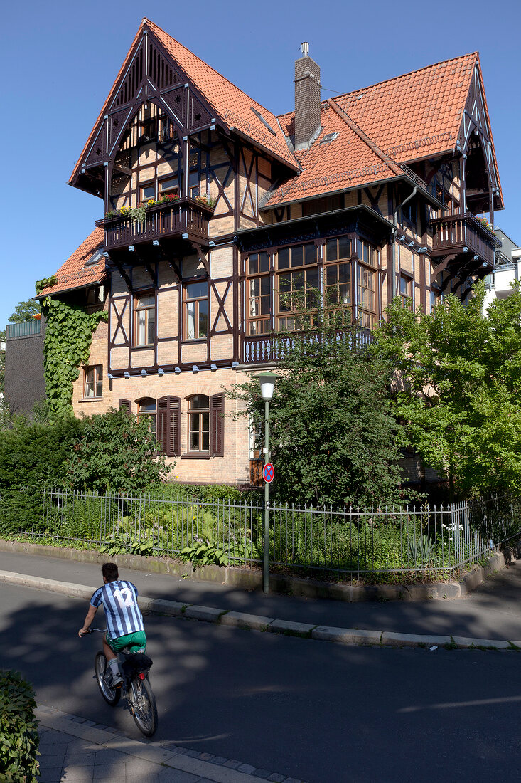 View of half-timbered villa with man cycling uptown, Kassel, Hesse, Germany