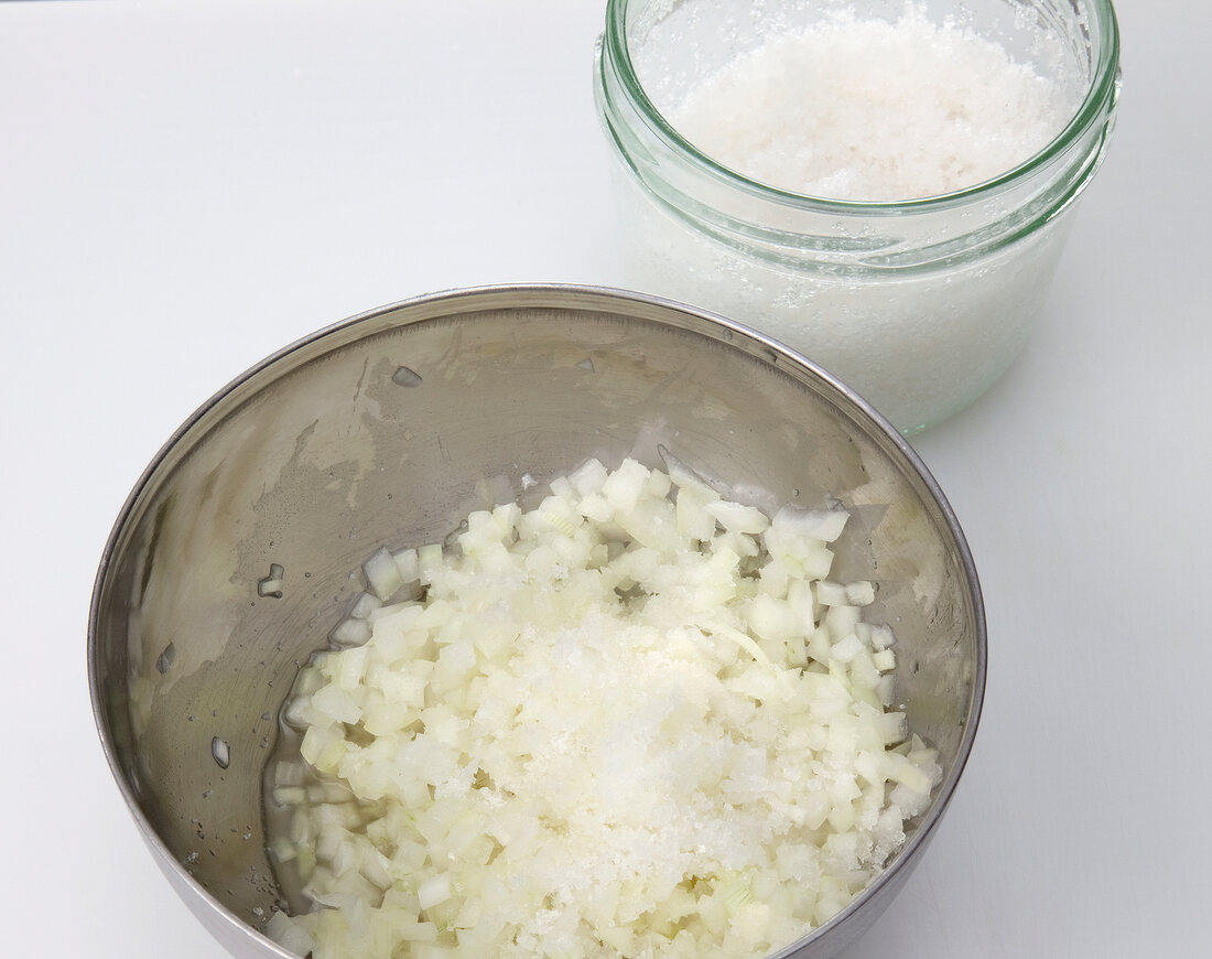 Salt sprinkled on chopped onions in bowl