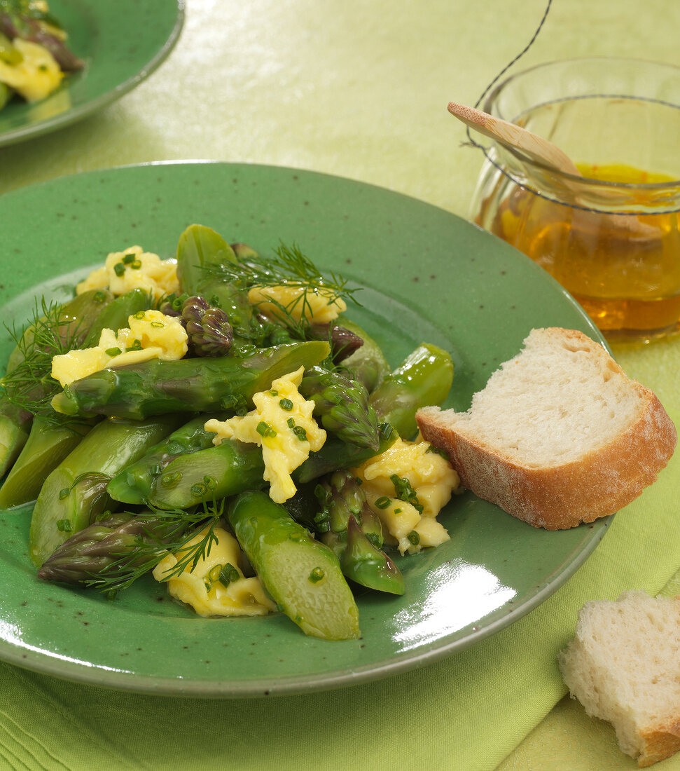 Asparagus salad with scrambled eggs and bread slice on plate