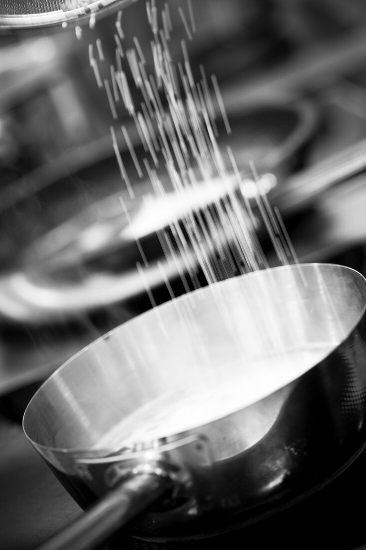 Close-up of salt being sprinkled in sauce pan