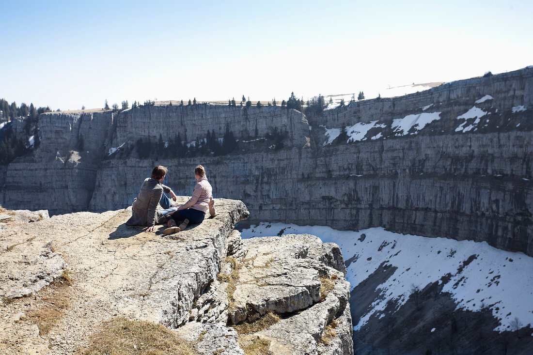 Couple sitting on rocks looking at canton, Jura, Scotland