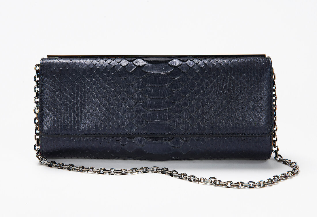 Close-up of black python print hand bag with chains handle on white background