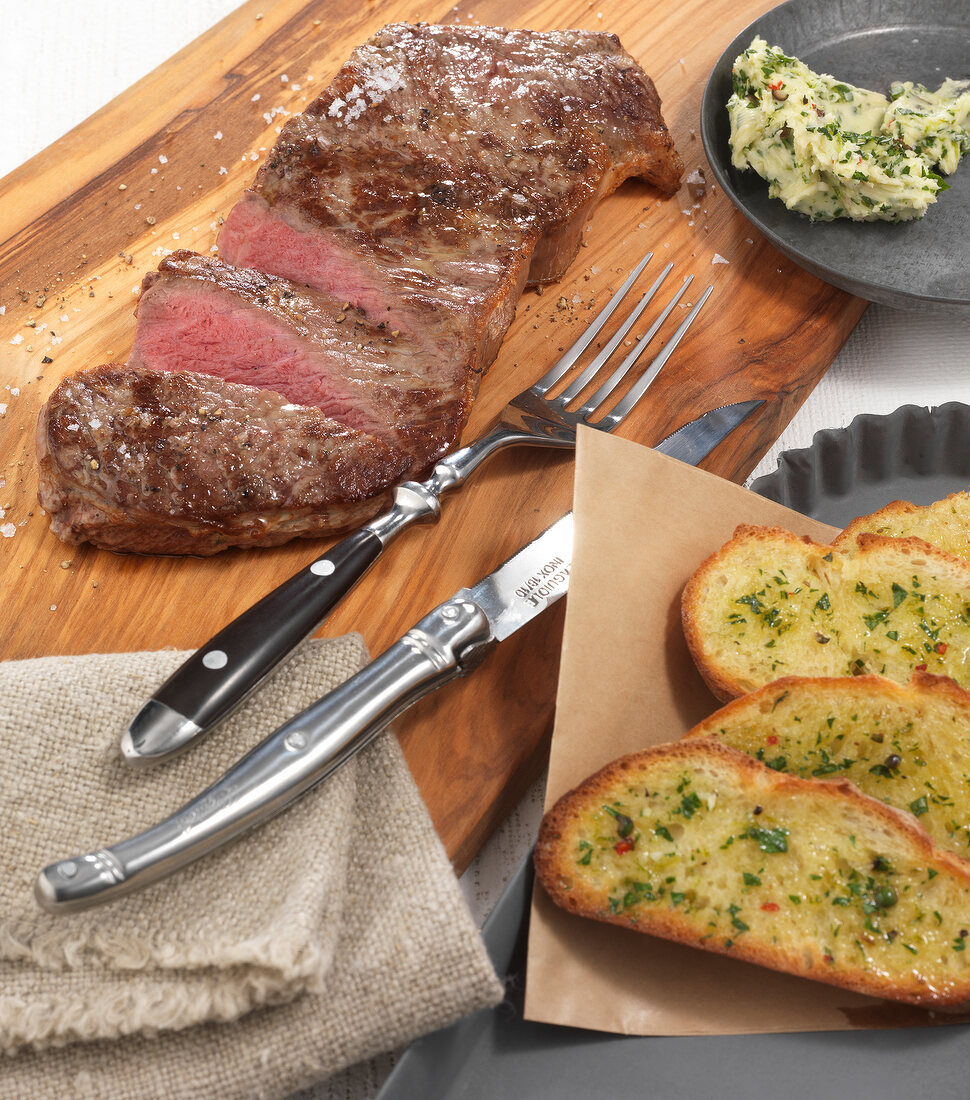Steaks with lime bread on cutting board