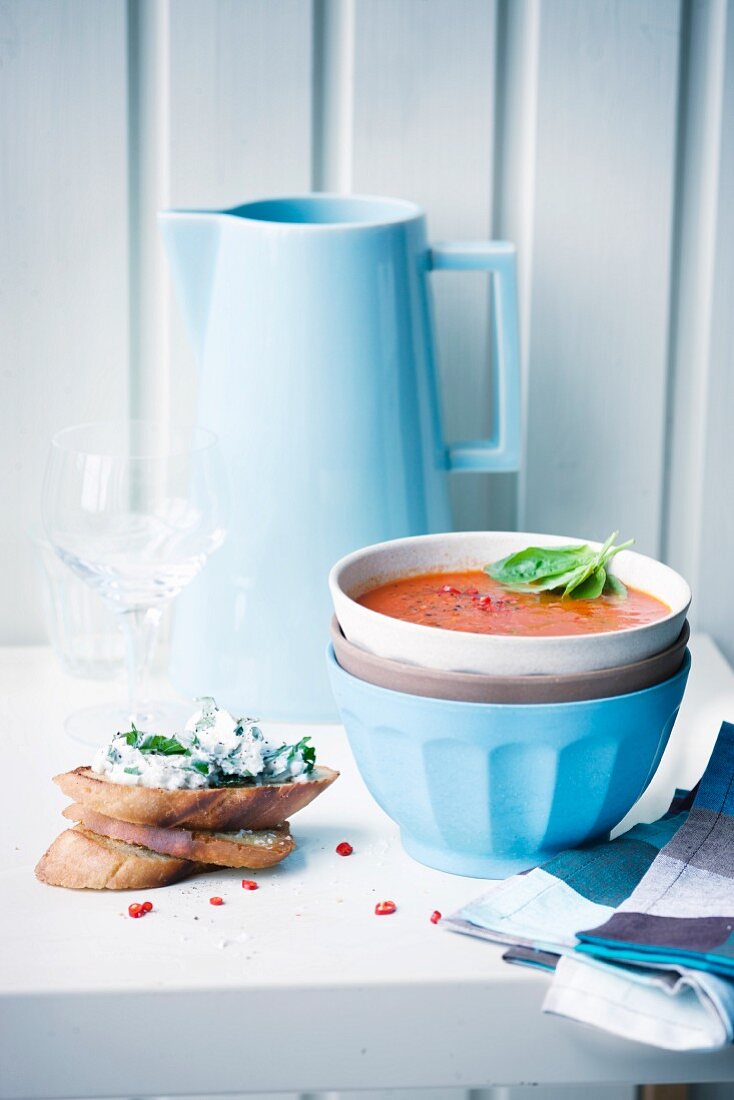 Spicy tomato soup with grilled bread in a soup bowl served with bread and cream cheese