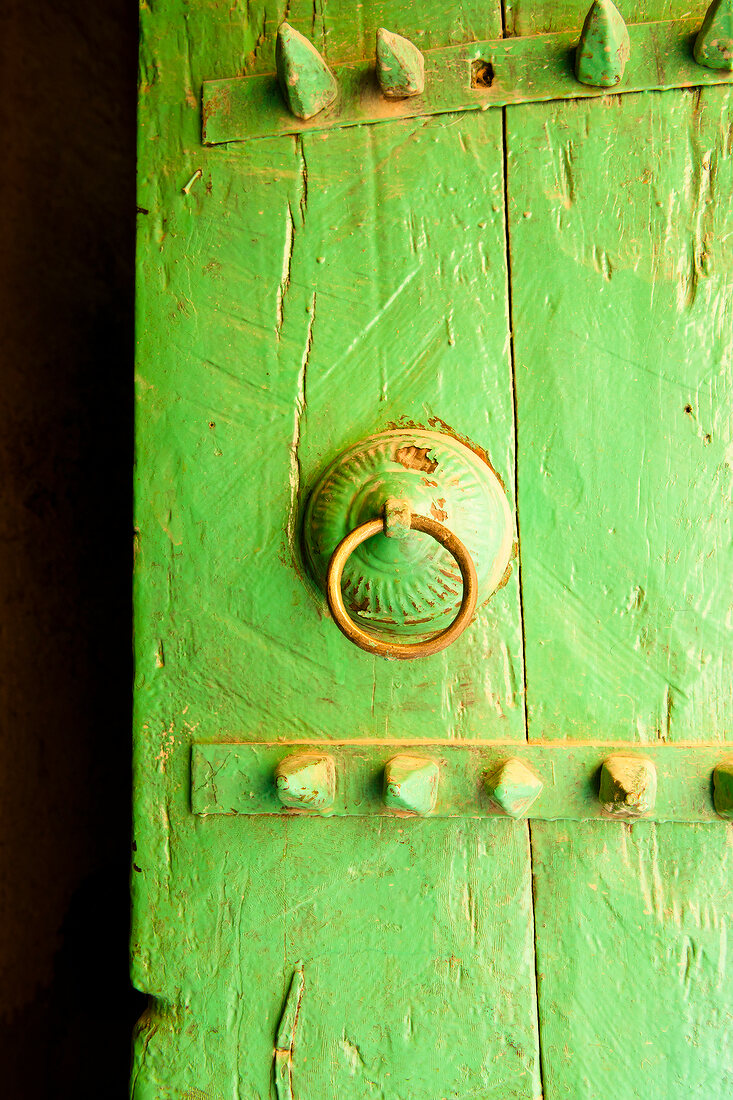 Close-up of green door with metal ring handle in Al Hamra, Oman