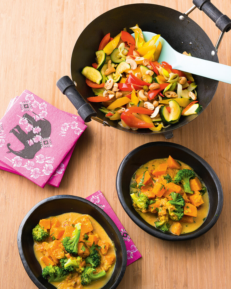 Sweet potato curry in bowl and roasted vegetables in wok