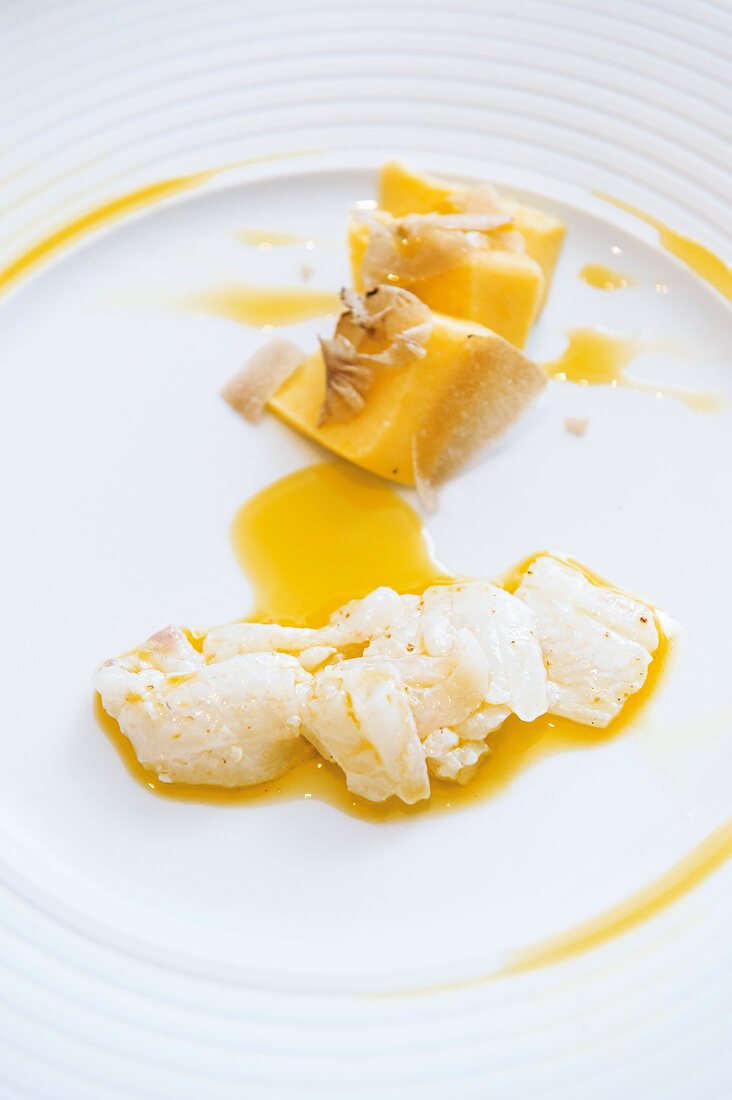 Close-up of raw plaice with polenta, summer truffles and olive oil