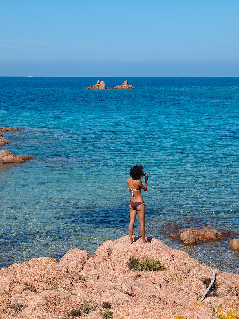 Woman in swimwear standing near Costa Paradiso in Sardinia, Italy