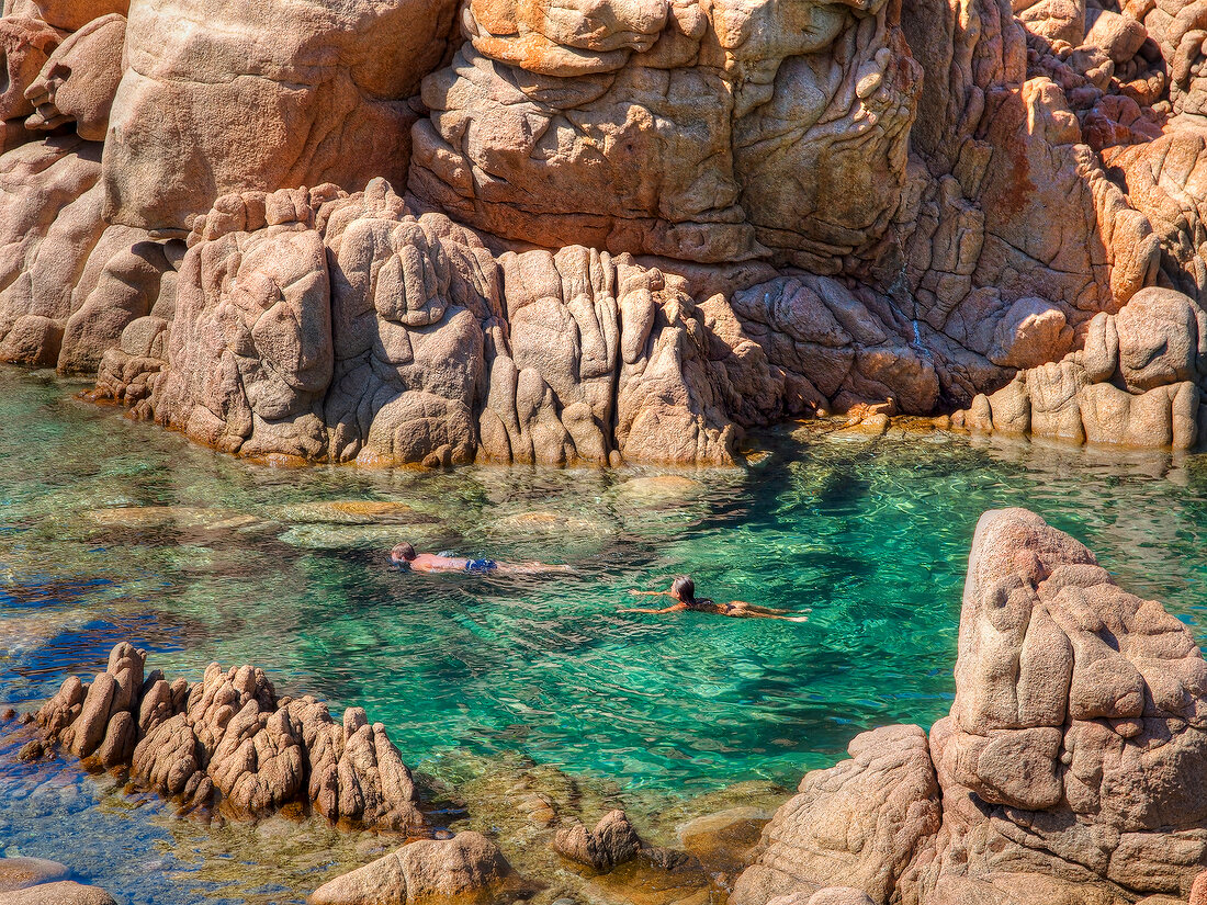 People swimming in sea near Costa Paradiso in Sardinia, Italy