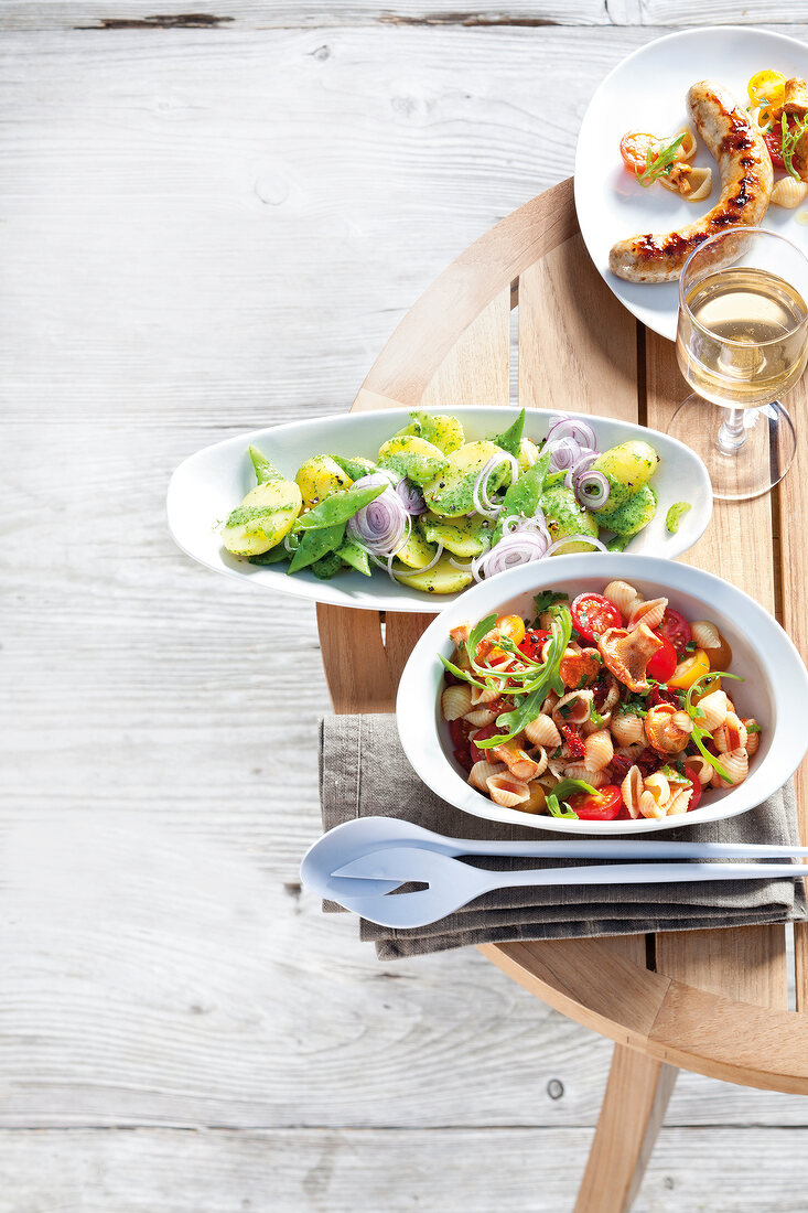 Potato salad with coriander and mint dressing in dish and pasta salad with chanterelles