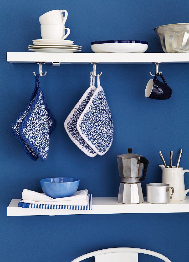 Kitchen utensils on white shelves on blue wall