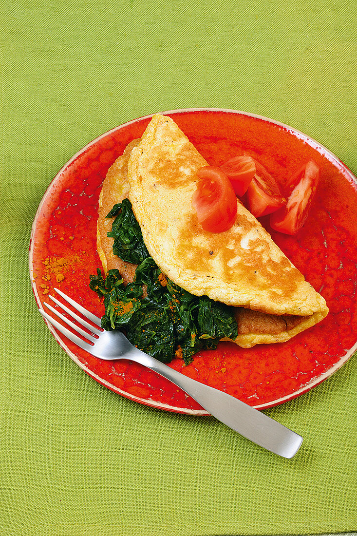 Omelette filled with spinach and tomato on plate