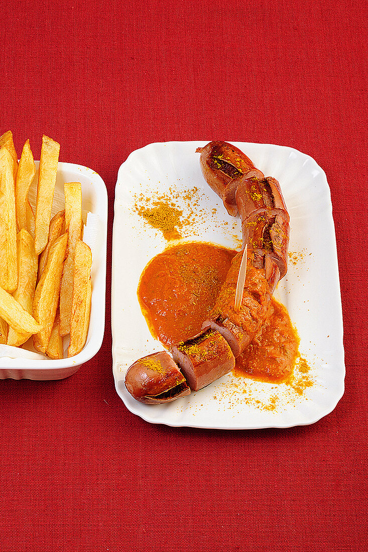 Currywurst with chips and sauce on serving dish