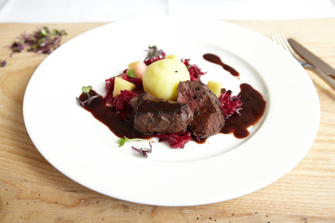 Mini-marinated beef venison with red cabbage and dumplings on plate