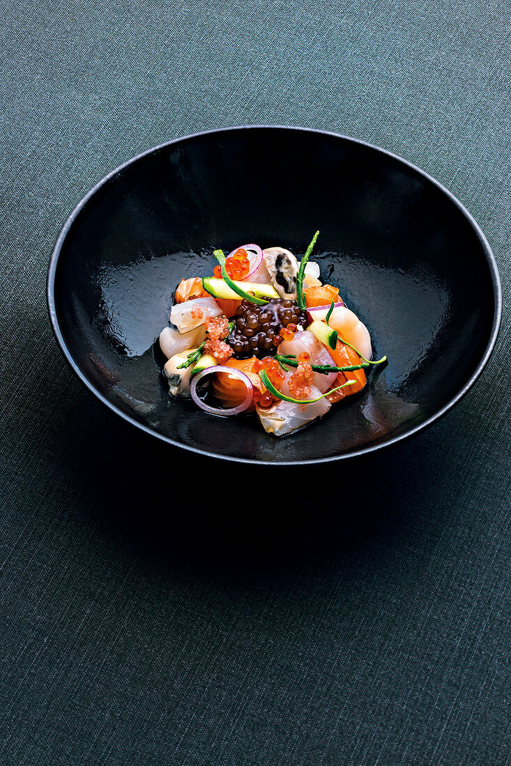 Scandinavian sashimi appetizer with salmon, shellfish and vegetables on plate