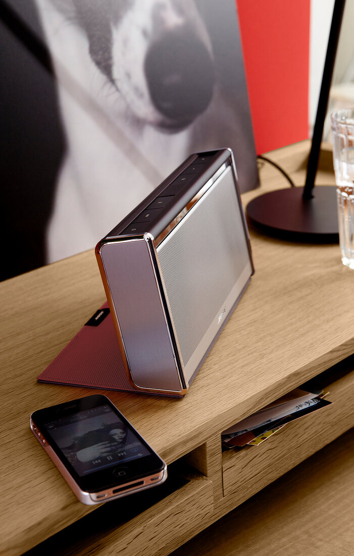Mobile phone and wireless speaker with leather cover on side table