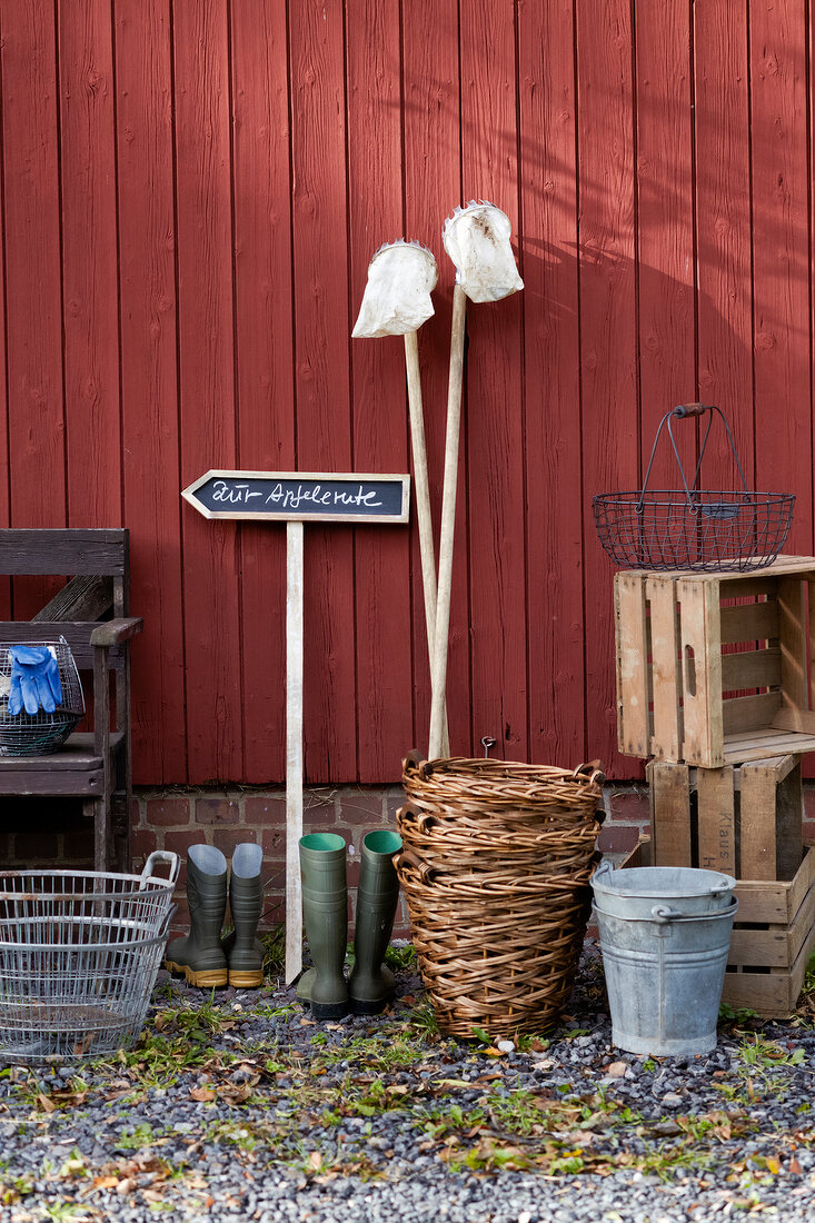 Apple picker basket, boxes and signpost against red wooden wall