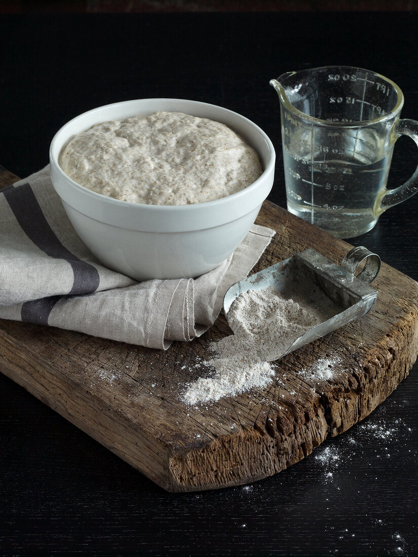 Brot, Schüssel mit rohem Hefeteig auf rustikalem Holzbrett