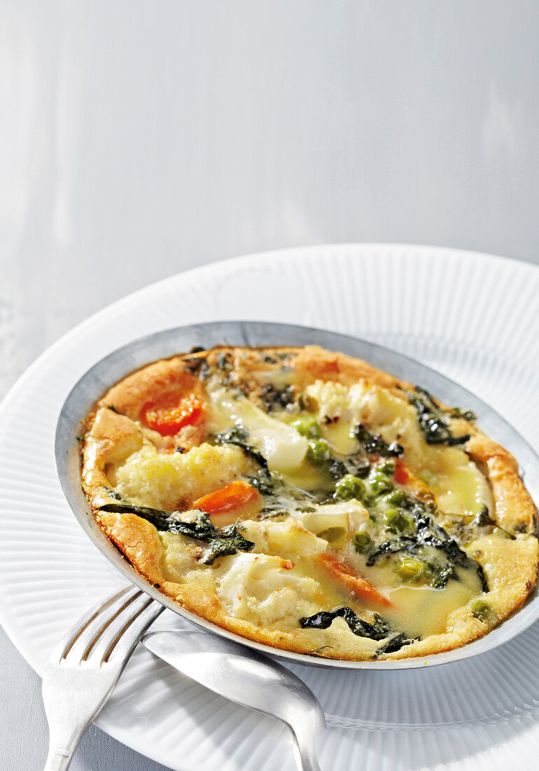 Clafoutis with garden vegetables and mustard butter on plate