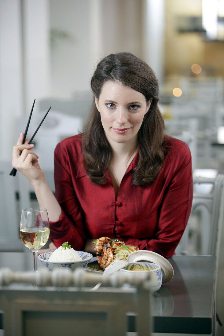 Frau mit langen braunen Haaren und roter Bluse im Restaurant