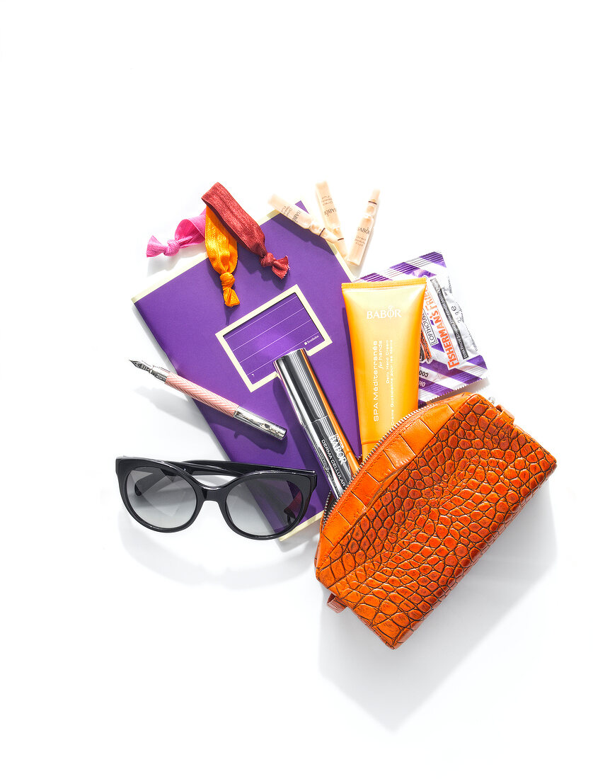 Handbag, sunglasses, book, make-up, cosmetics and pouch on white background, overhead view