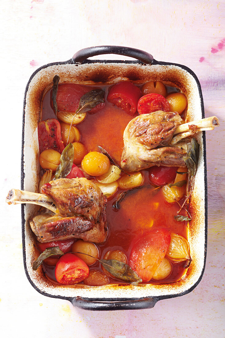 Lamb stilts with sage, tomatoes, apricots, casserole and roaster in serving dish
