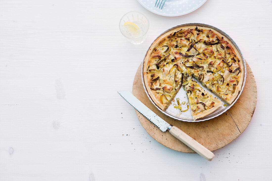 Leeks and pear tart on plate on pink background