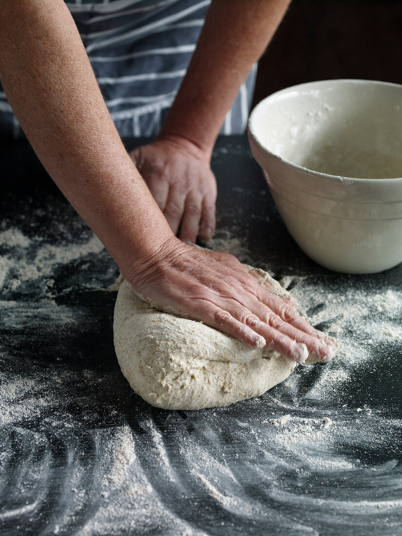 Close-up of hand kneading dough for preparing bread, step 3