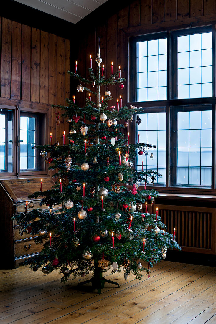 Christmas tree decorated with lit candles and silver jewellery