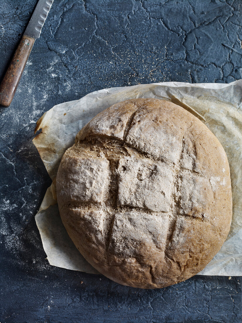 Round loaf of white bread on baking paper