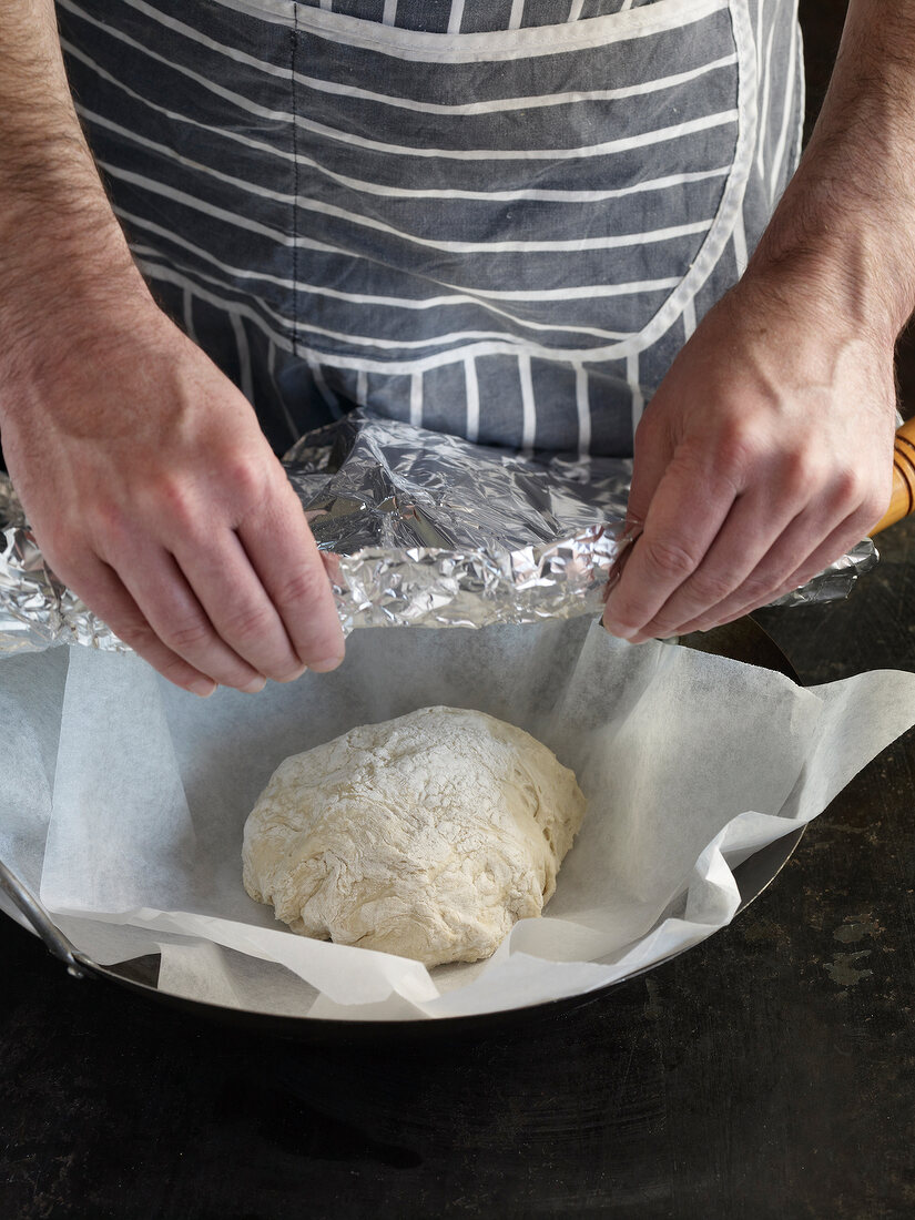 Close-up of hand wrapping dough in aluminium foil