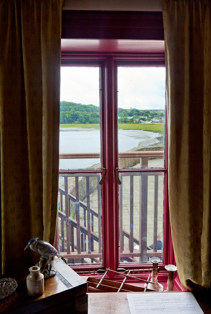 View of lake from boat house window with curtains, Laugharne, Carmarthenshire, Wales, UK