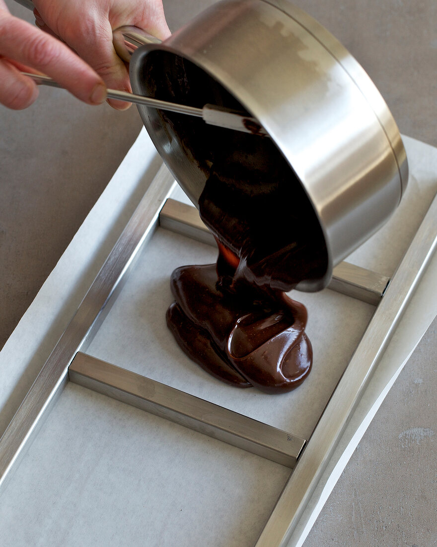 Close-up of hand pouring melted chocolate in mould, step 1