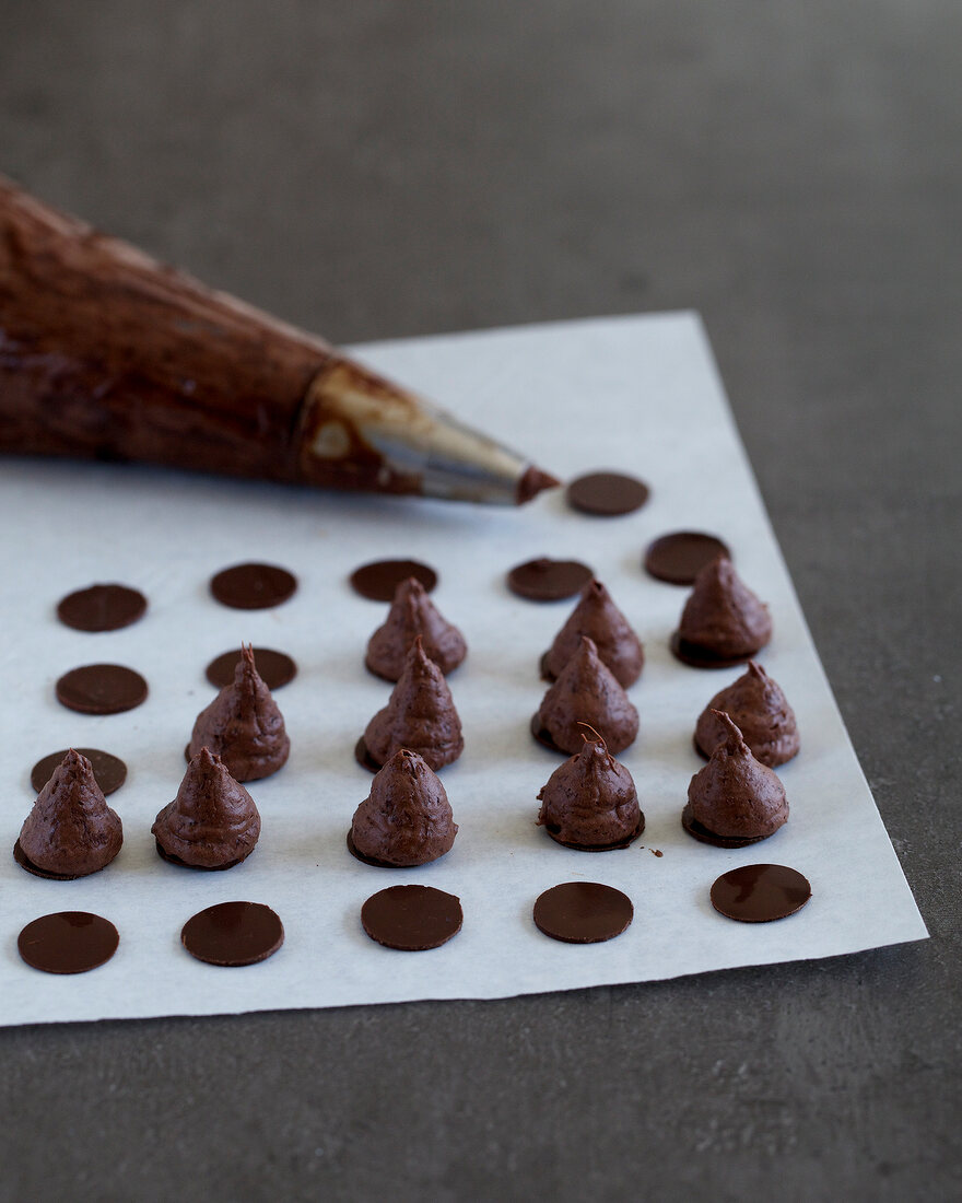 Dollops of chocolate mousse made on circles of chocolate with piping bag, step 3