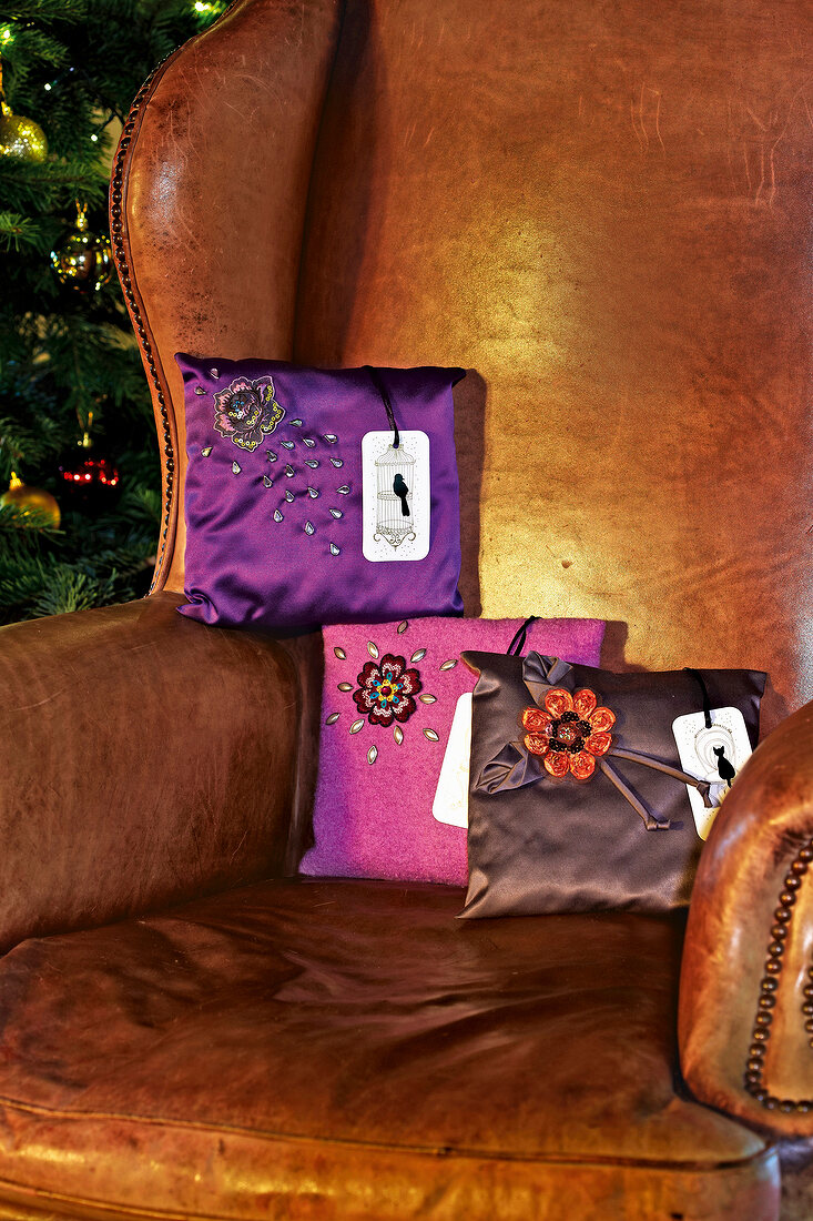 Satin pillows decorated with glitter flowers on armchair
