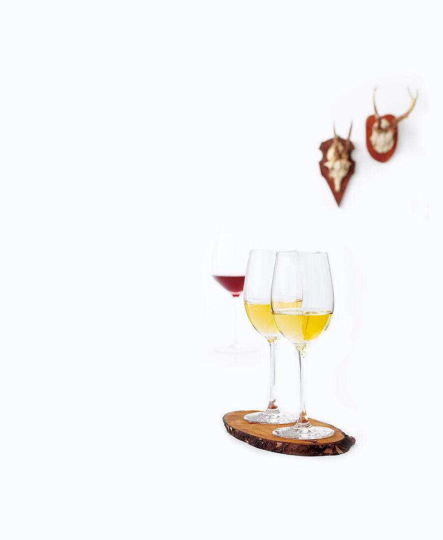 Two white wine glass on wood against white background