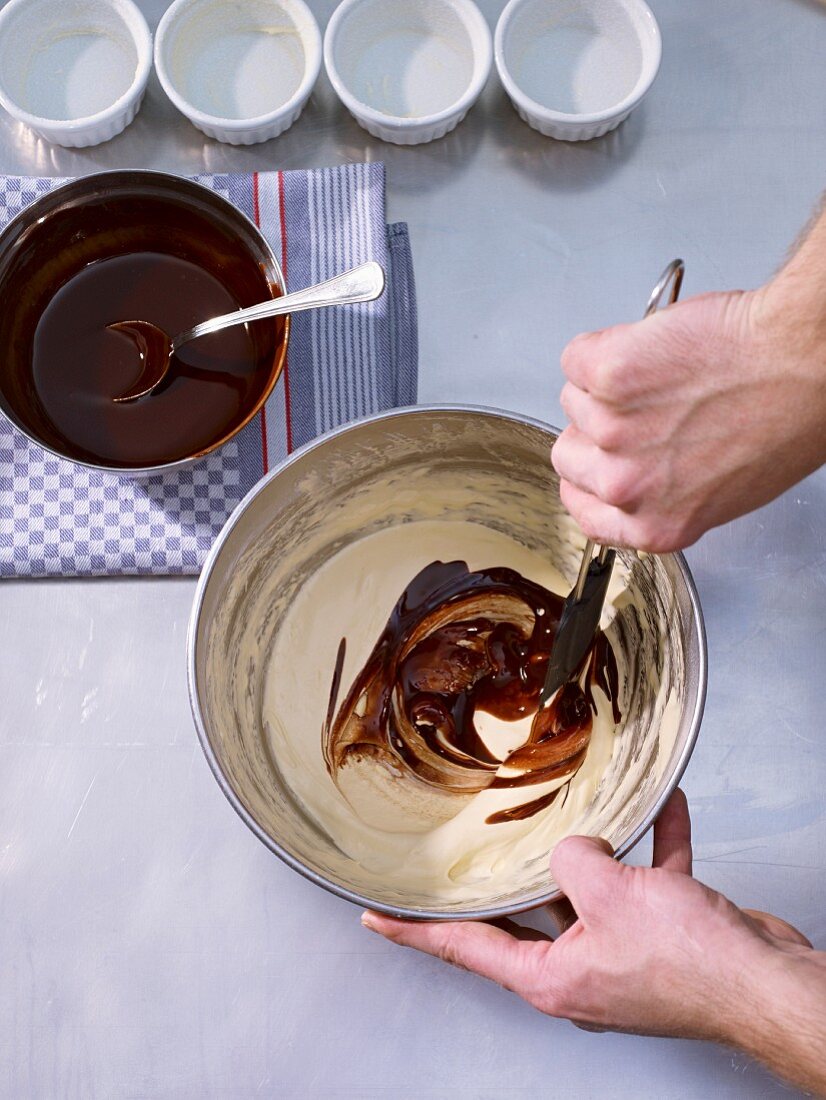 Butter and chocolate mixture being added to an egg yolk-sugar mixture