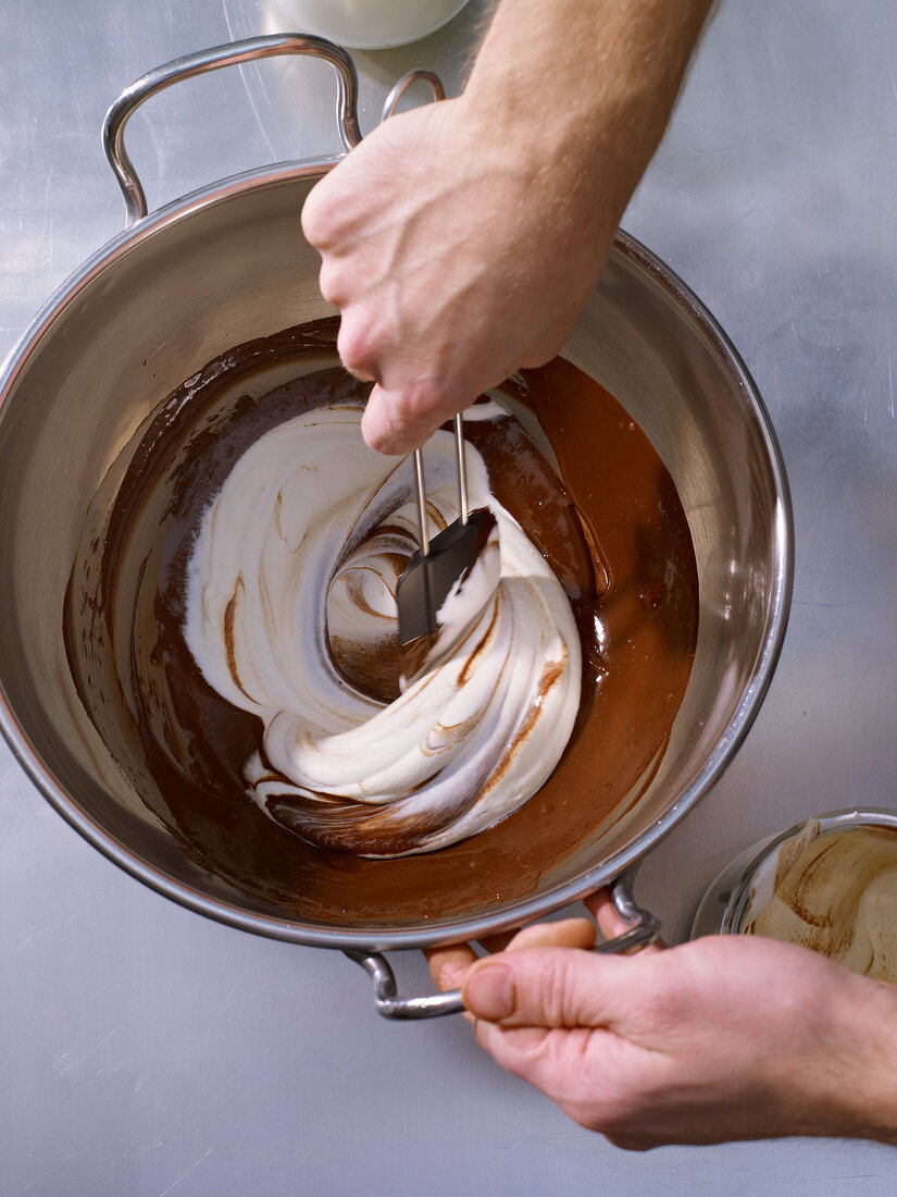 Mixing cream with chocolate mixture in bowl