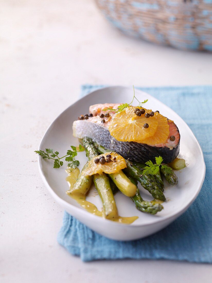 Baked salmon with asparagus and orange butter on plate in serving dish