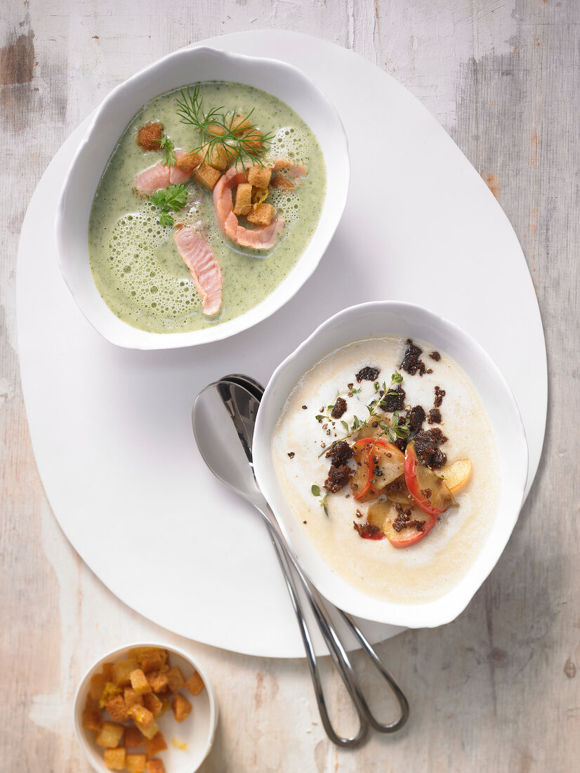Green foam soup with salmon and potato in bowl and celery soup with apples