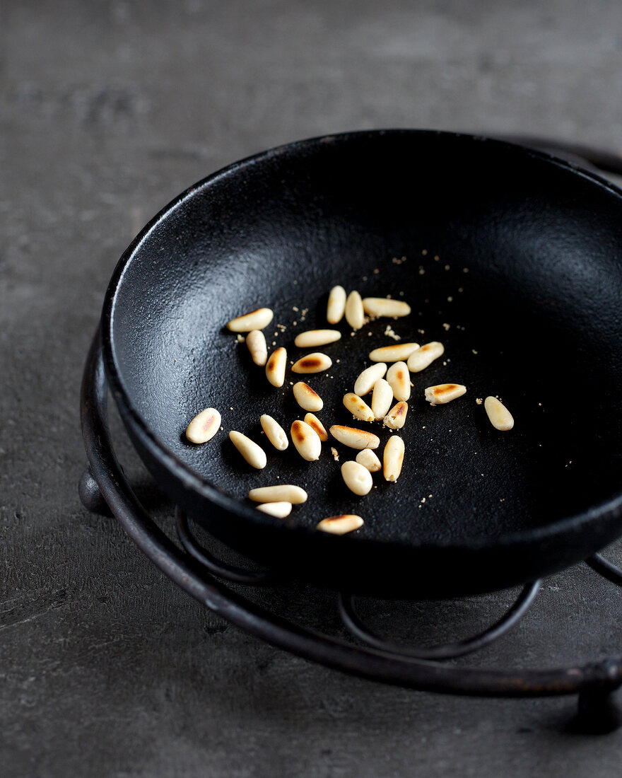 Roasted pine nuts in pan for preparation of chocolate lollipops, step 1