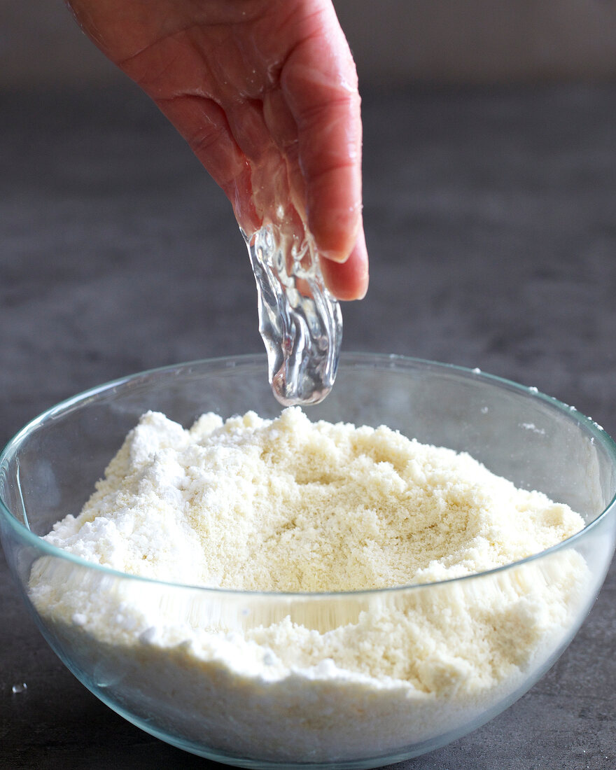 Close-up of egg white being poured in bowl of dough for preparing marzipan