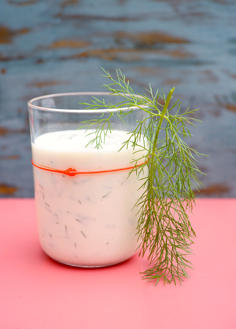 Glass of drink garnished with dill leaves