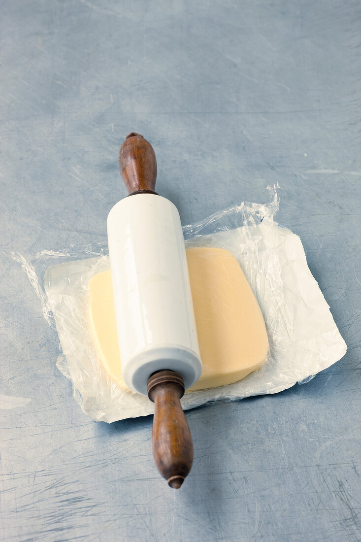 Butter being made flat with rolling pin for preparing pastry, step 1