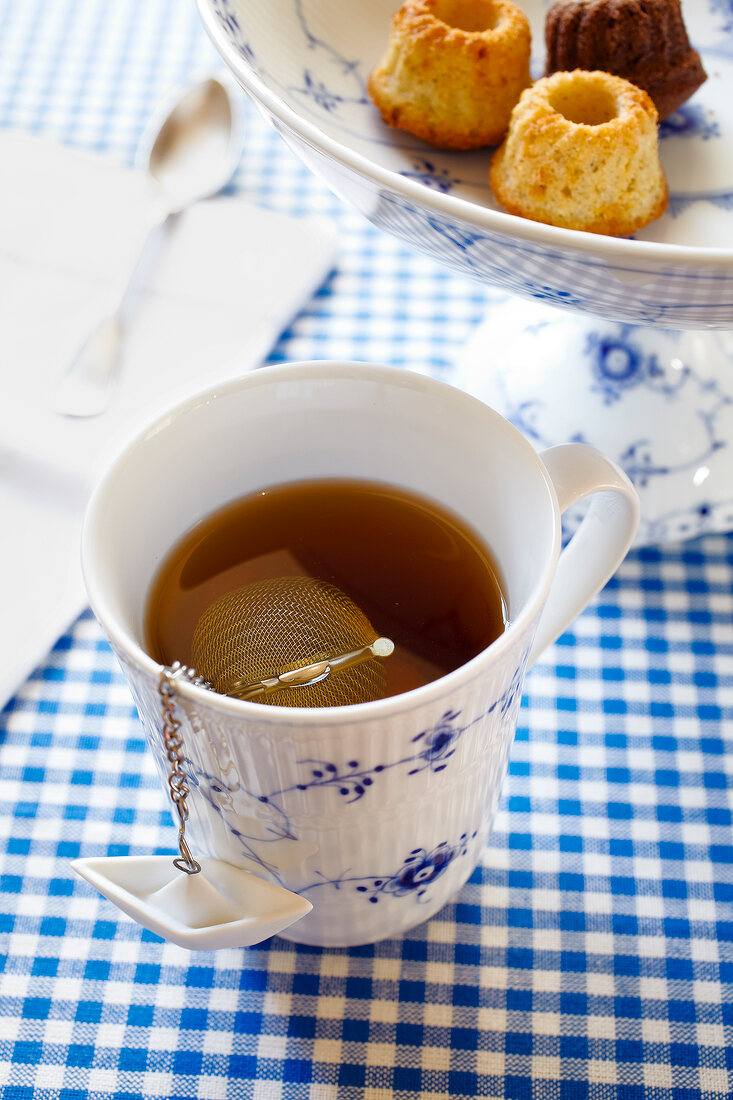 Porcelain cup filled with tea and mesh tea infuser ball