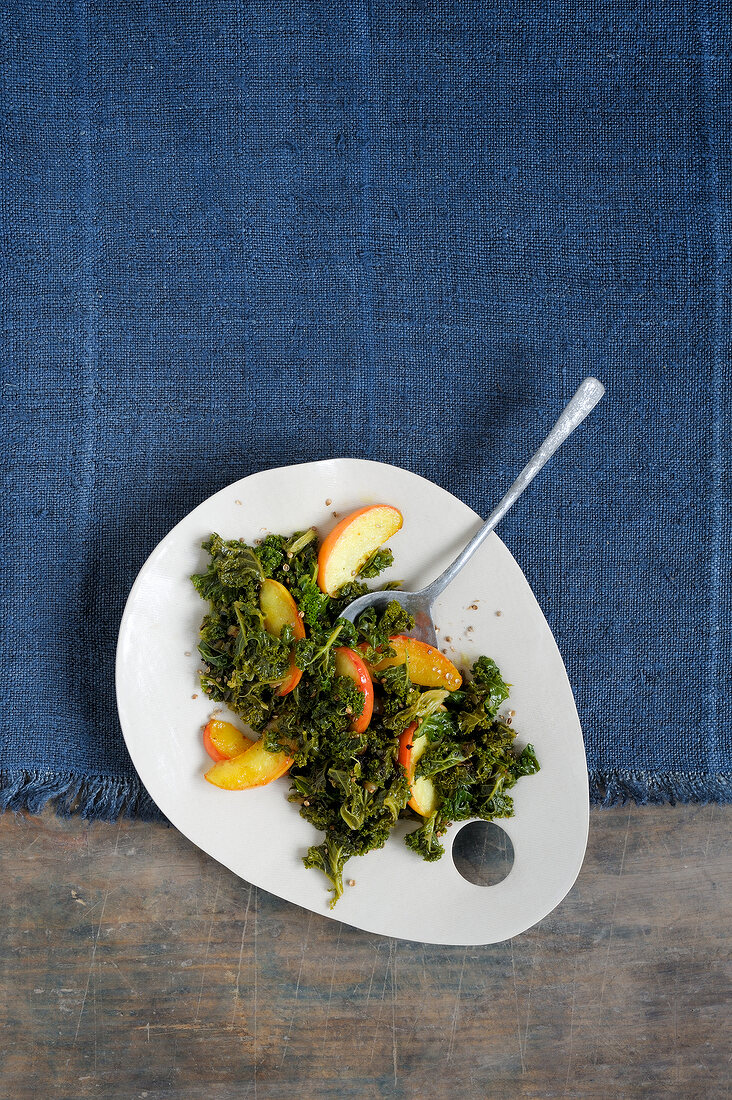 Green cabbage with apples on plate, overhead view