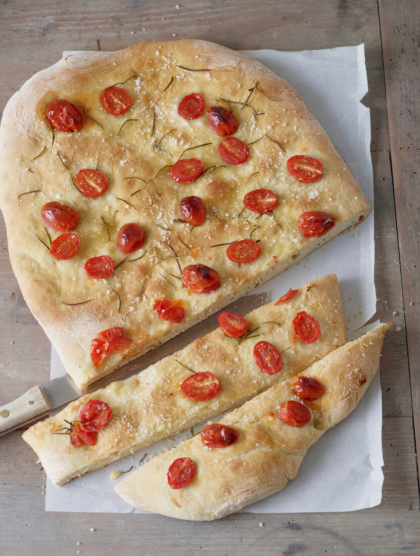 Slices of focaccia with rosemary and grape tomatoes on paper