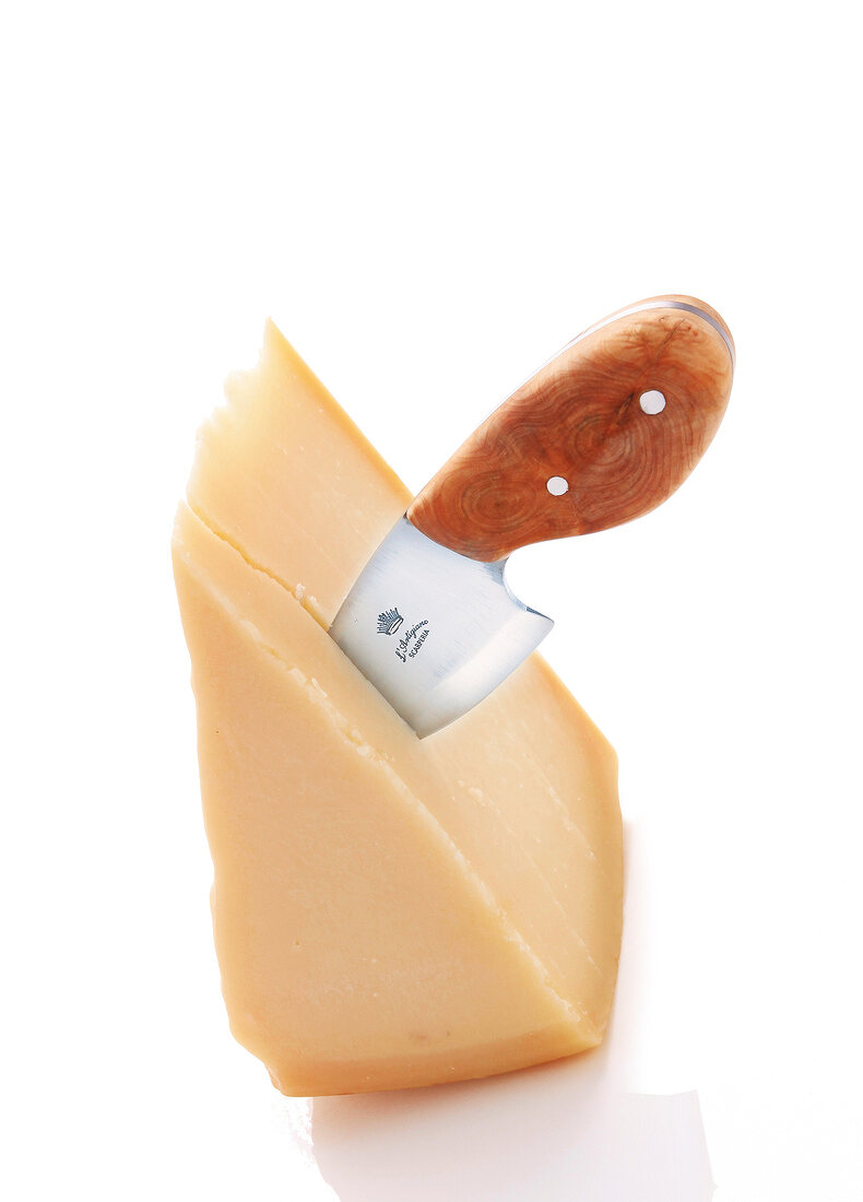 Parmesanmesser steckt in einem Stück Parmesan, Käse, Grana