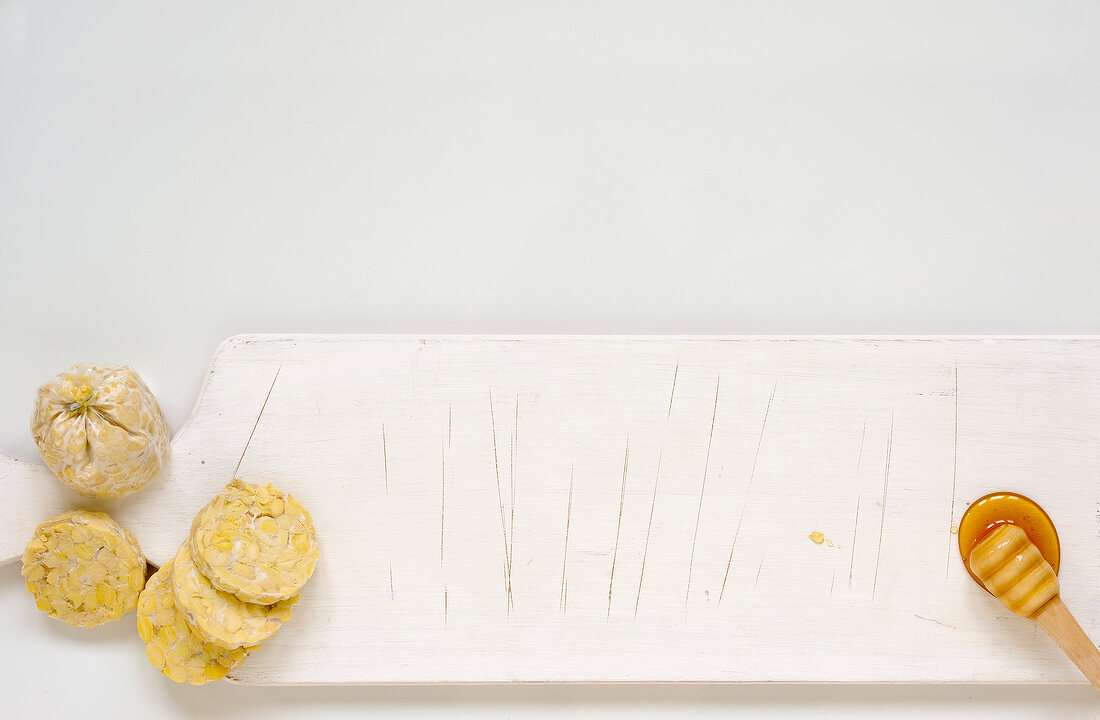 Honey dipper and tofu on chopping board