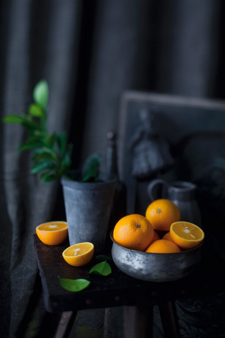 An arrangement of oranges in a bowl and on a stool